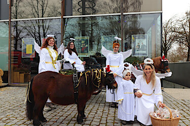 Zwei weihnachtlich geschmückte Ponys sowie als Engel verkleidete Frauen und ein Kind vor dem Puchheimer Kulturcentrum PUC